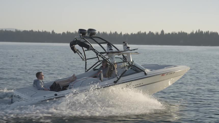 Three people relax as they ride in a speedboat across the water