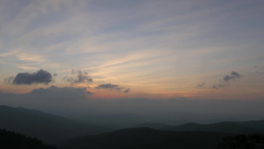 Dawn or dusk with clouds moving over a hilly valley