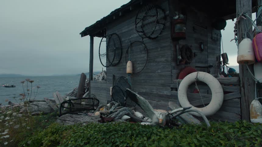 Flotation devices and crab pots hang on a shack near the coast on a windy day