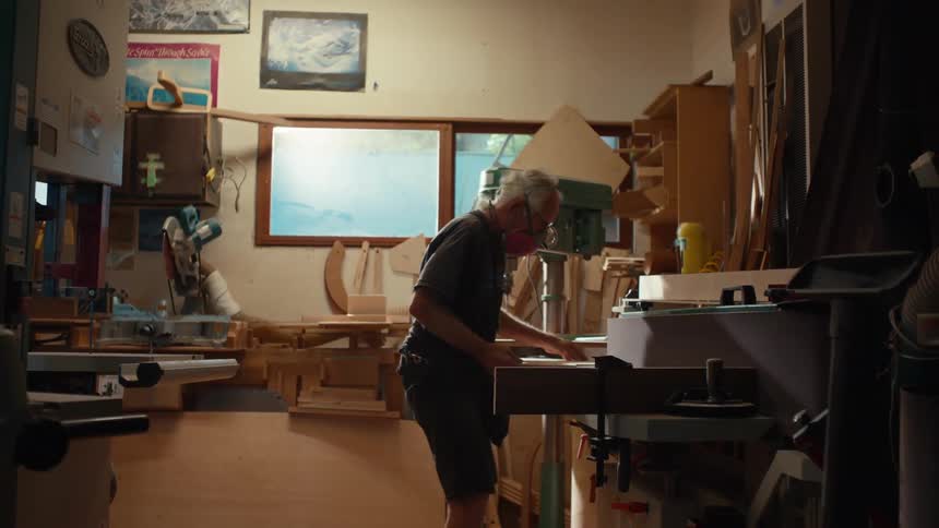A well equipped woodworking workshop with a person working on a project with walls lined with tools and various woodworking equipment