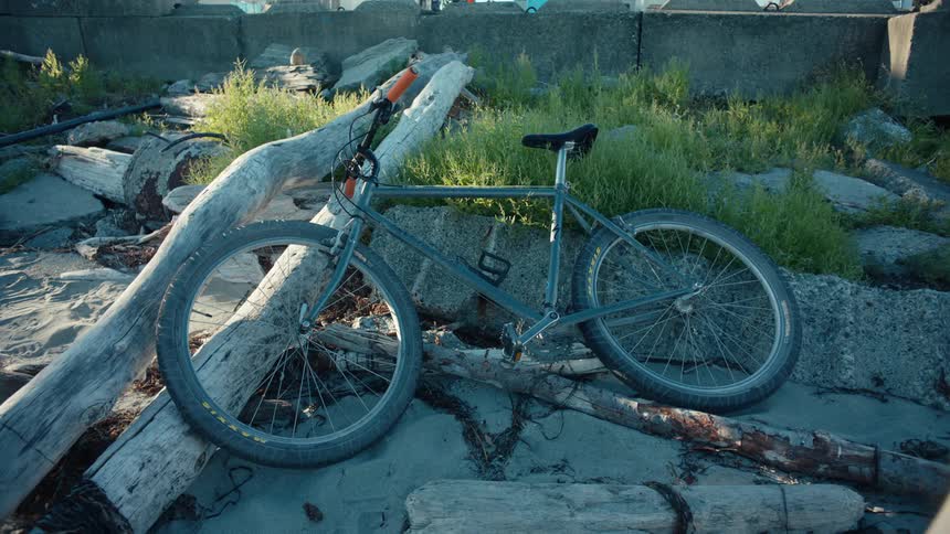 Bicycle thrown on the ground among rocks and wooden logs