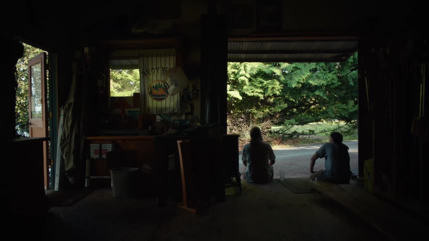 Two men sitting outside a warehouse talking