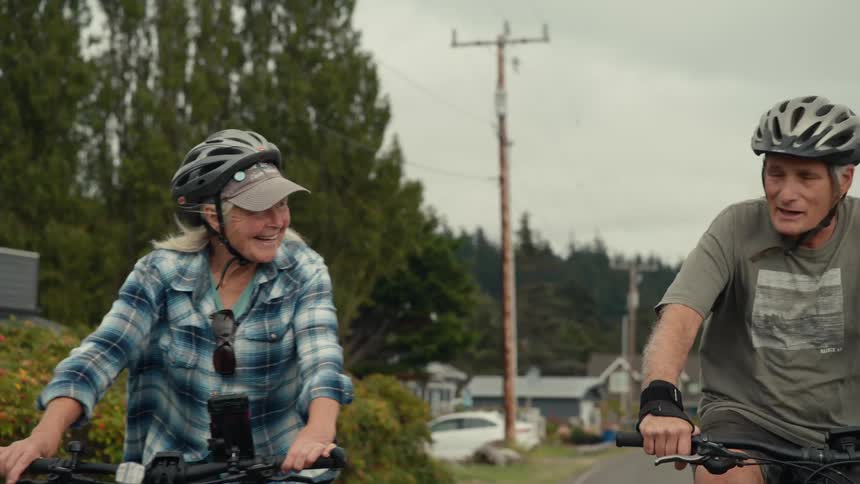 Happy older couple riding thier bikes through a neighboorhood