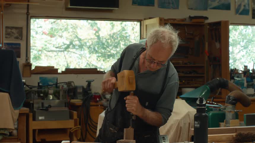 Elderly carpenter hammering an object