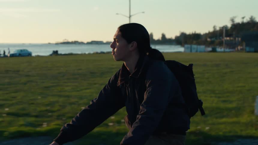 Man with backpack riding a bike through a field