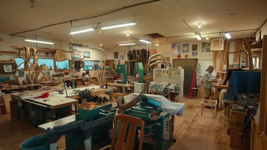 A wellequipped woodworking workshop filled with tools and materials with a craftsman working diligently at a workbench
