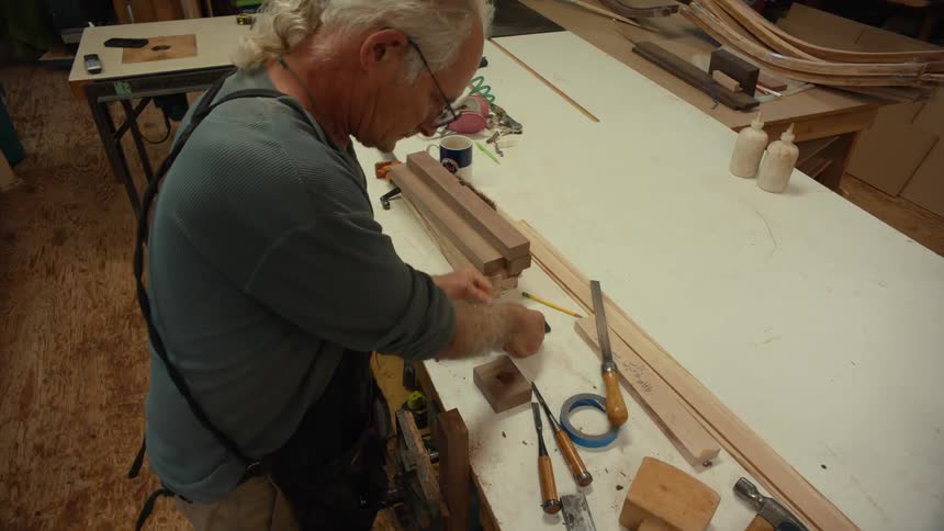 Man working on a piece of wood indoors on a table