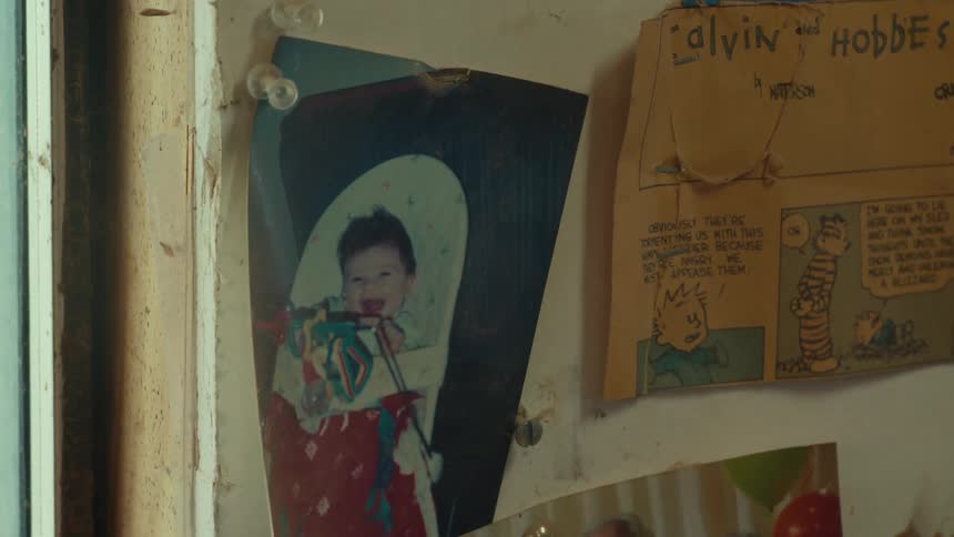 A photo of a smiling little child hanging on a white wall and next to it a small page from an old comic book