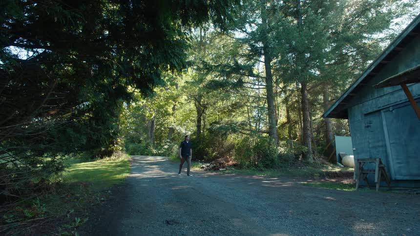 Man walking along a trail and heading towards a house
