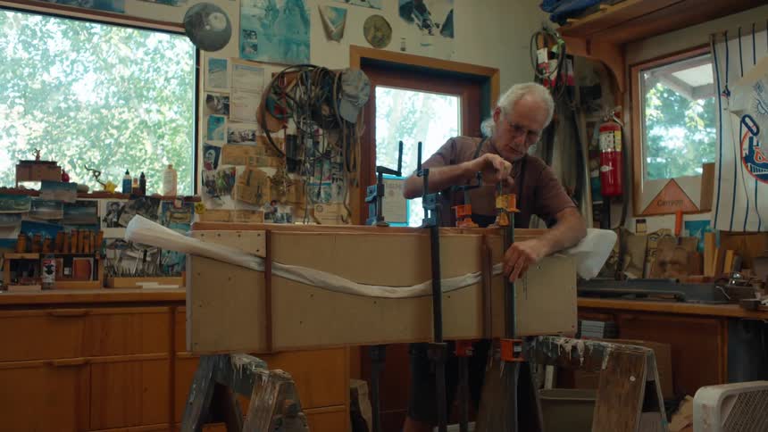 A man is tightening clamps in a workshop