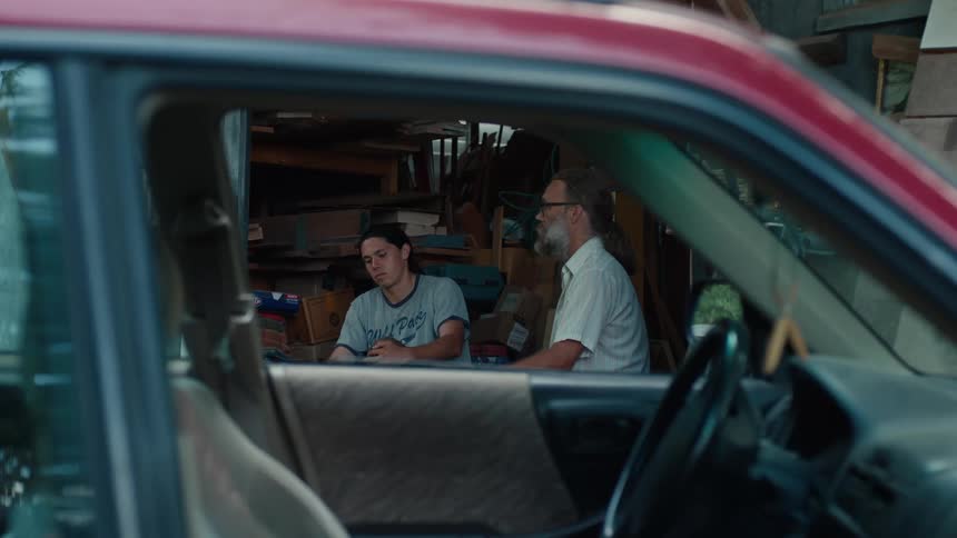 Two men sitting talking seen through a car window