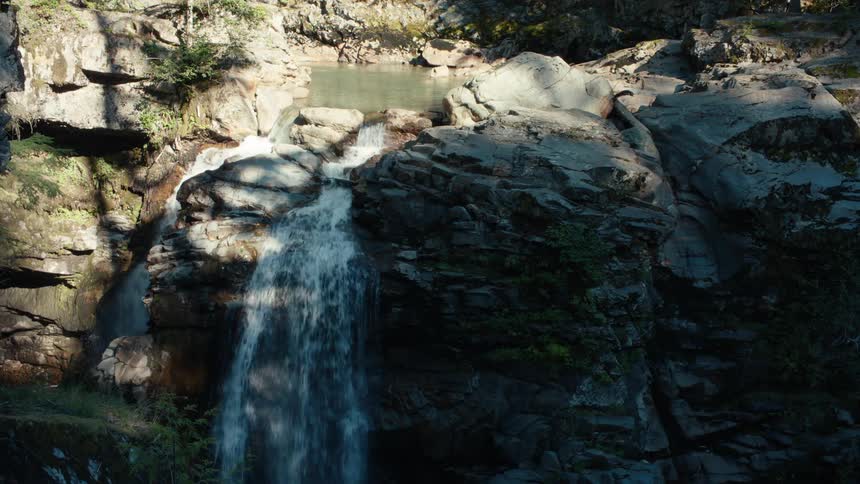 Water forms a pair of waterfalls while falling over the edge of a cliff