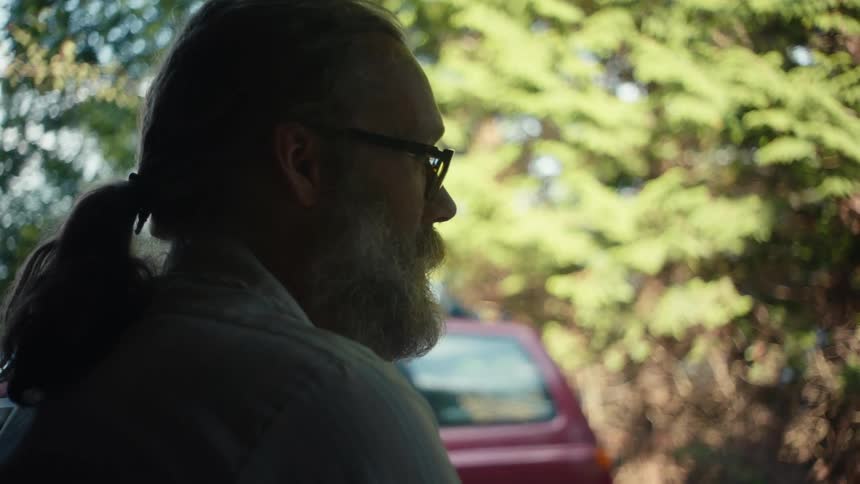 Side portrait of a bearded man with glasses talking