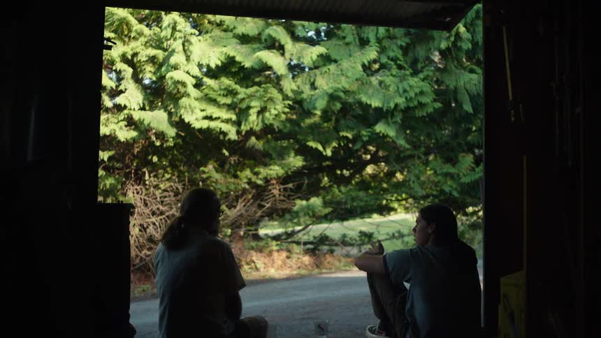 Two men sitting outside a door talking to each other