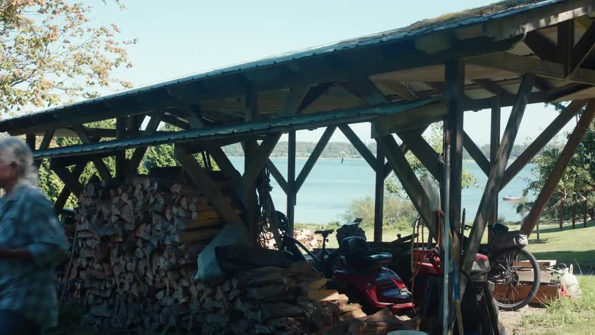 Elderly woman walking in a yard with chopped firewood nearby