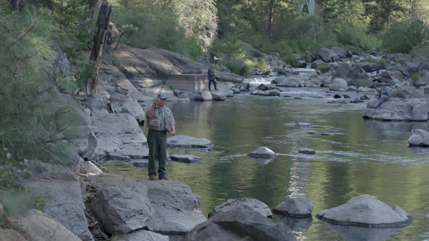 Two men fly fish in a rocky river