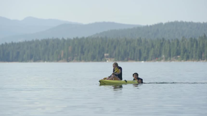 A boy pushes a girl on a raft as she paddles