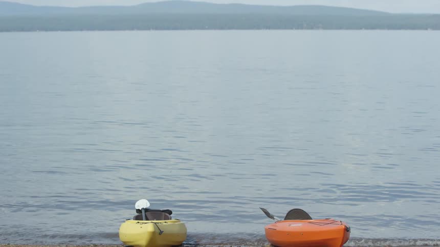 Two kayaks parked at the edge of water