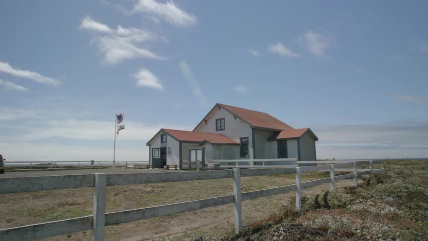 A view of a house with a flag pole and fenced in yard
