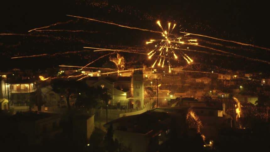 Fireworks shooting across a city and exploding at night