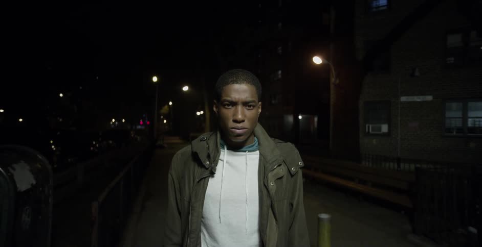 A man stands on a street at night
