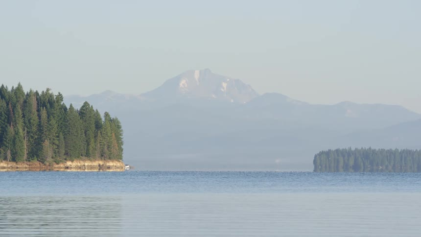 A lake surrounded by trees with a mountain peak in the distance