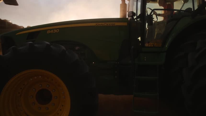 A large farm truck carrying a dump truck behind it in a plantation on a sunny morning