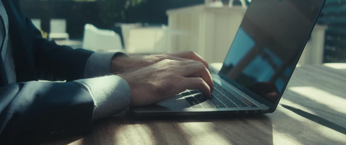 Man types on a laptop computer outside