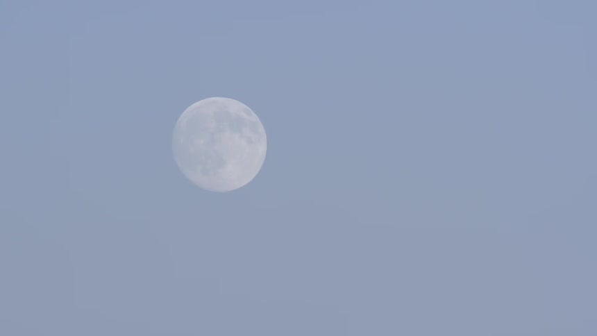 A moon is high in a cloudy sky