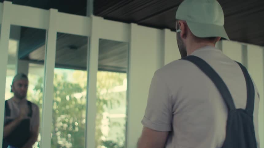 Man in cap cleaning house and listening to music