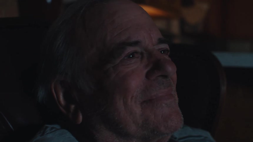 Elderly man sitting in an armchair watching with happy facial expression