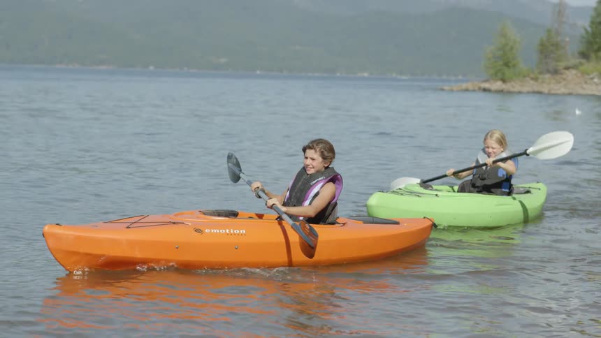Girls kayak on a lake on a sunny day