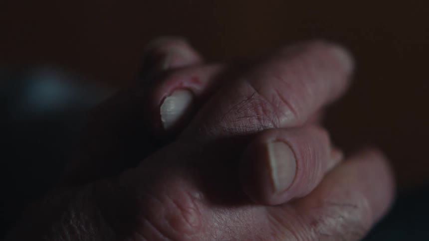 Hands crossed by an apprehensive elderly person