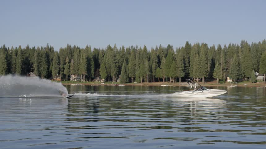 A man wake boards on a lake on a sunny day