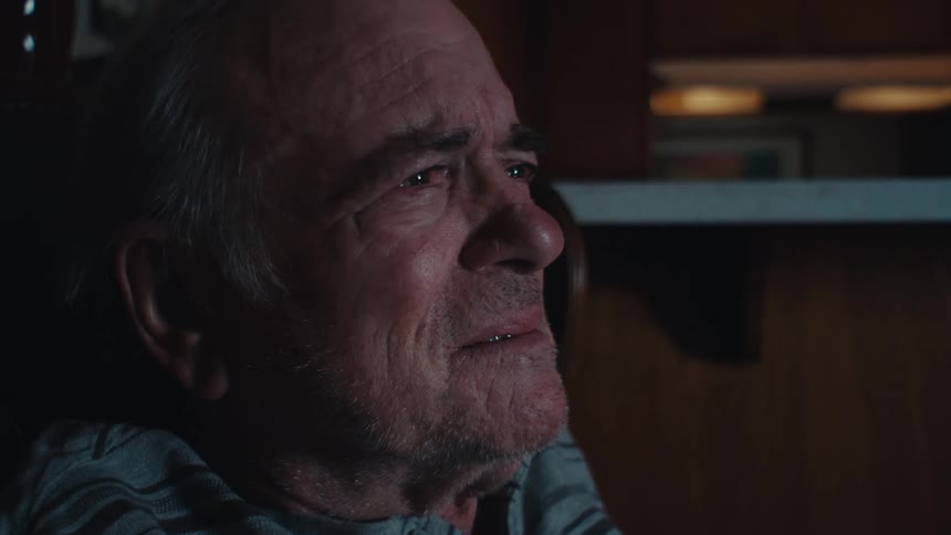 An elderly man crying and sobbing while watching tv