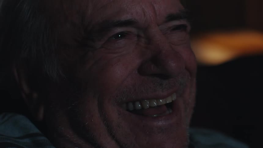 A man is laughing as he watches television