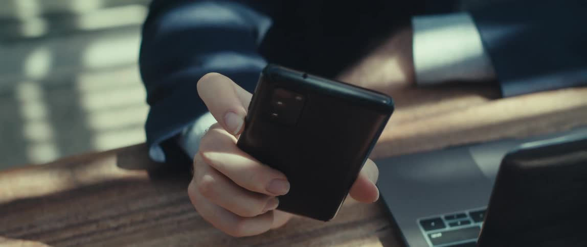 Man interacting with a smartphone and a laptop while sitting