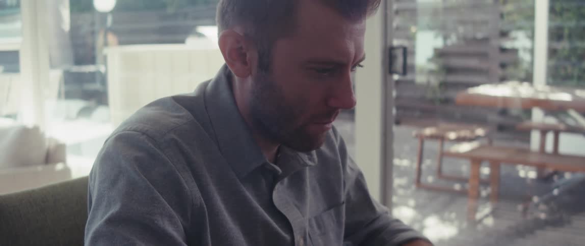 Man sitting typing on laptop and looking to side
