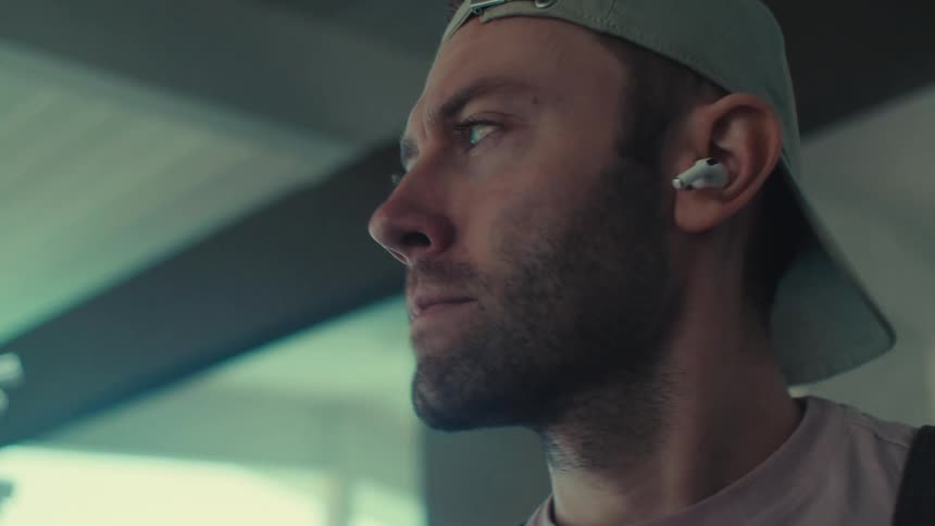 Man in gray cap using airpods and gesturing with head