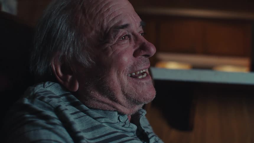 Side portrait of an elderly man sitting and laughing