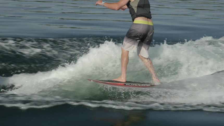A man riding on a wake surf and surfing on water