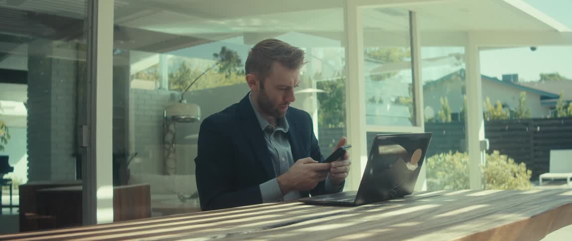 Man ending a call and typing on laptop
