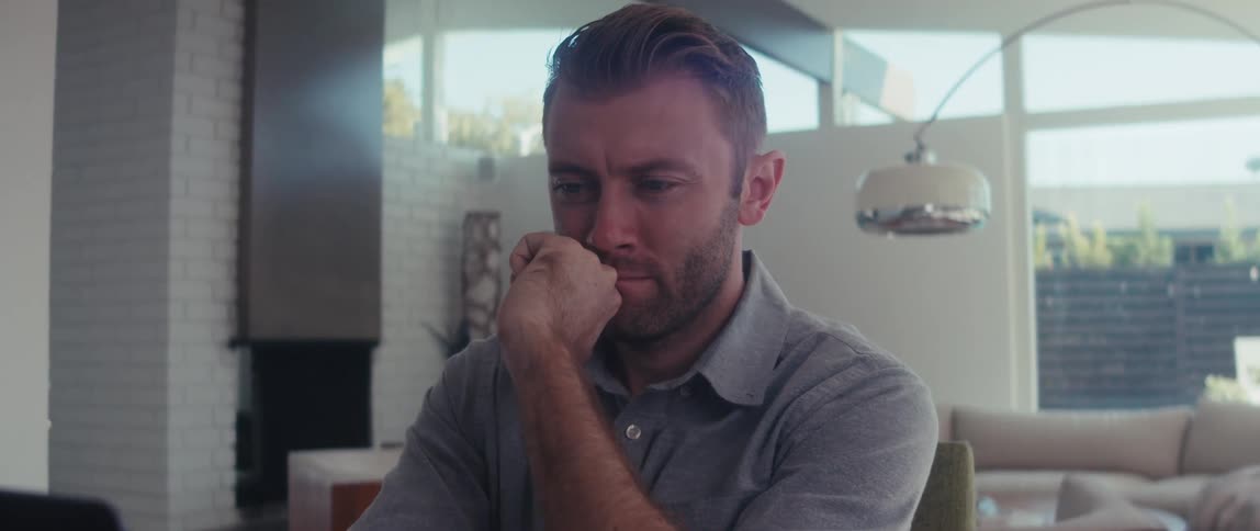 Man sitting with hand on chin in front of a laptop