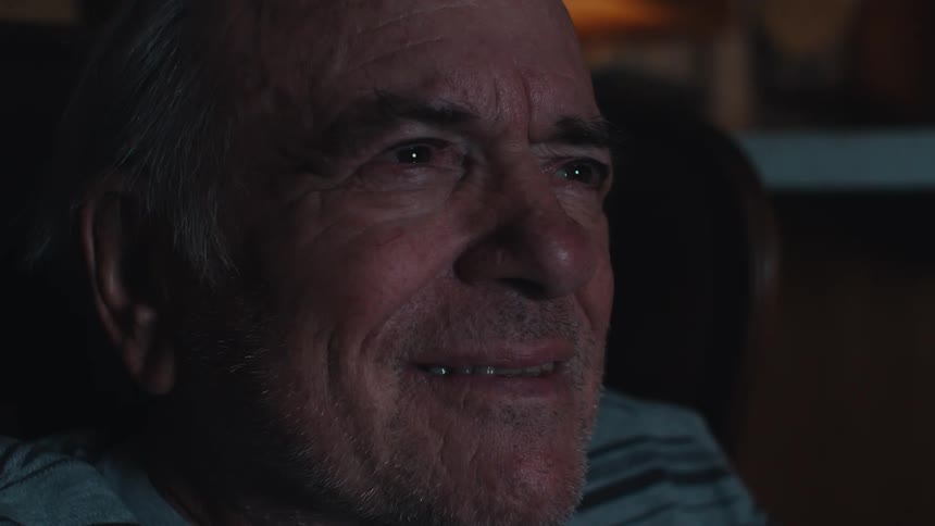 A man is smiling as he watches tv