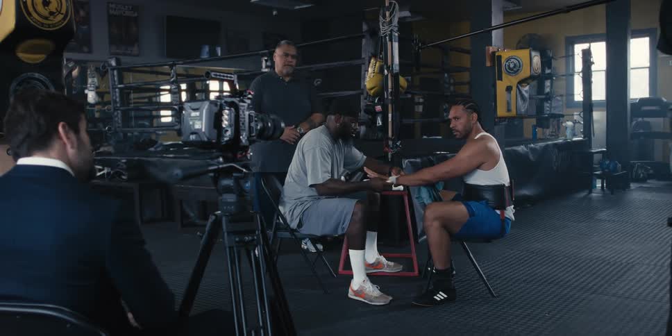 Fighter with serious expression sitting on a chair while another man holds his hand