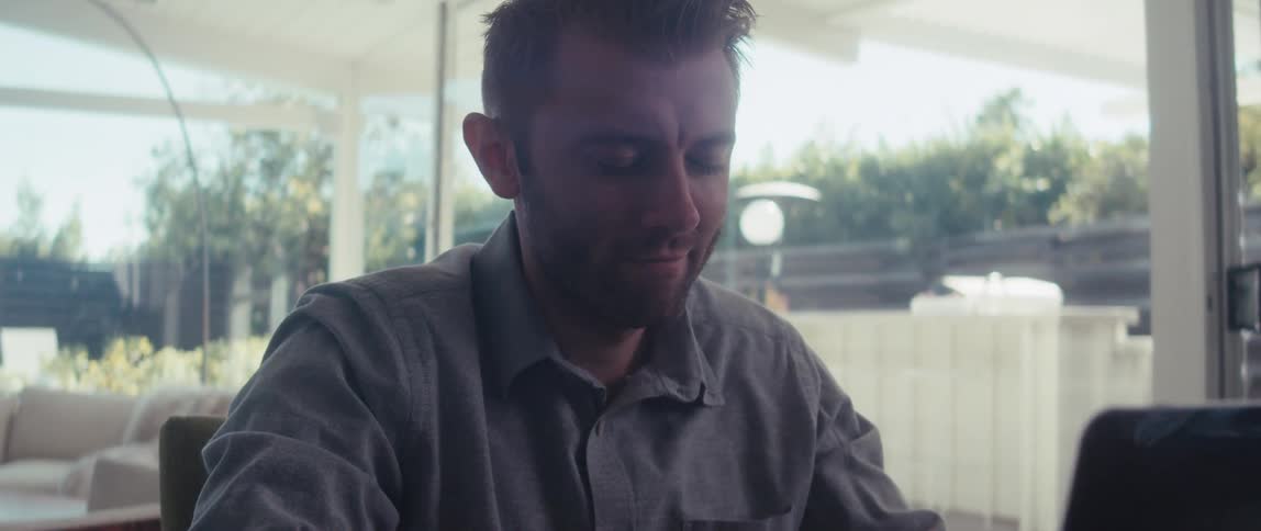 Man sitting at desk interacting with his open laptop