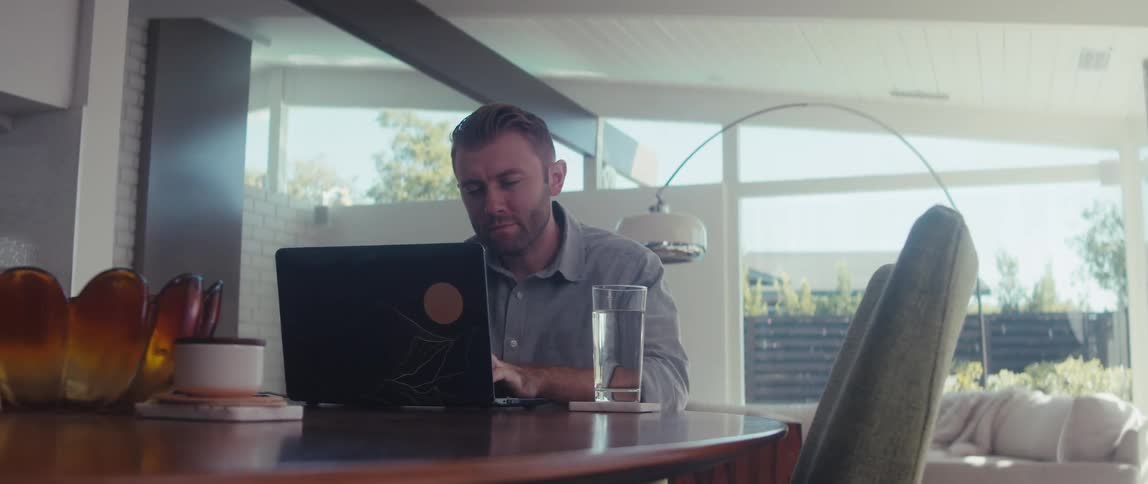 Man sitting at a table typing on laptop