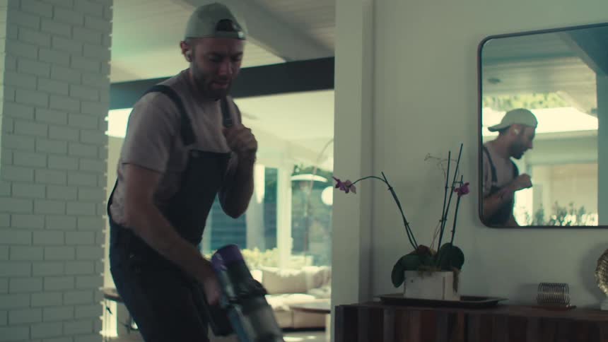 Man having fun while cleaning the house dancing
