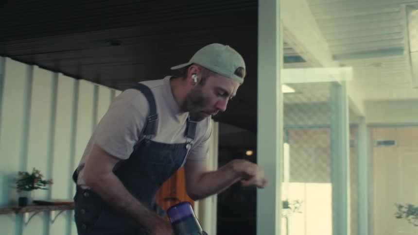 Man dancing and enjoying music while vacuuming a room in the house