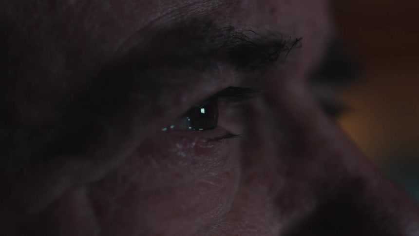 An elderly man crying while watching tv